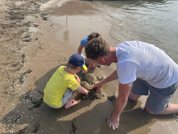 Children exploring the muddy shoreline of a natural water environment, discovering nature during an outdoor adventure.